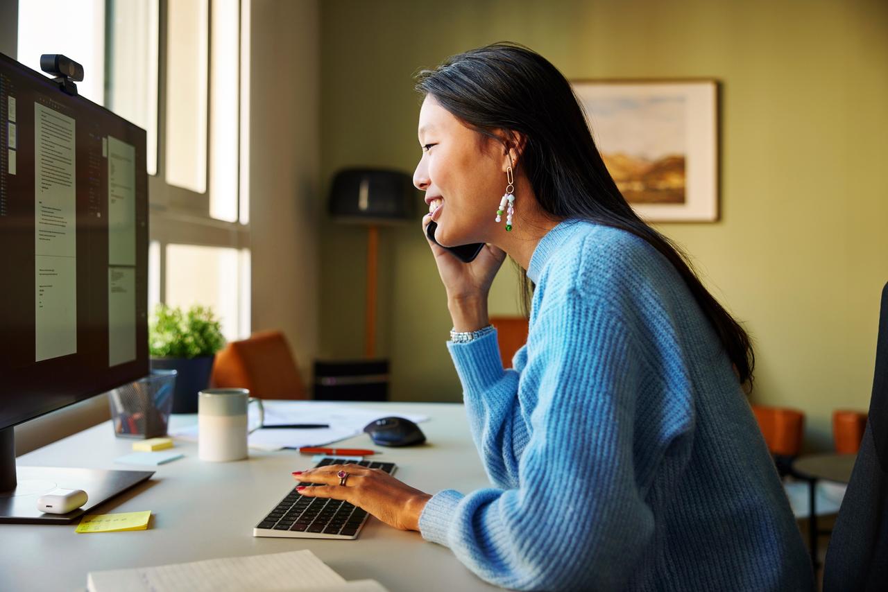 Lady_talking_on_smart_phone_at_desk.jpg