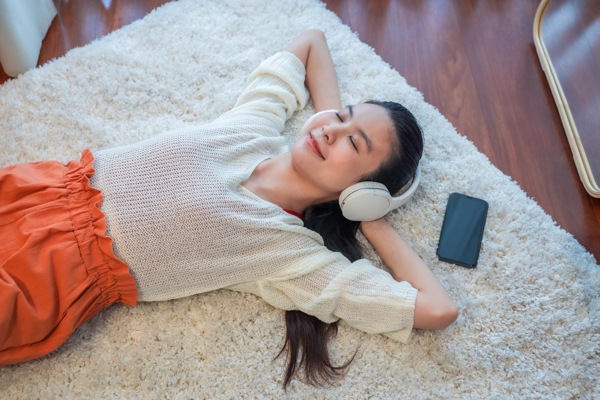 Woman_laying_down_on_rug_with_mobile_listening_to_music.jpg